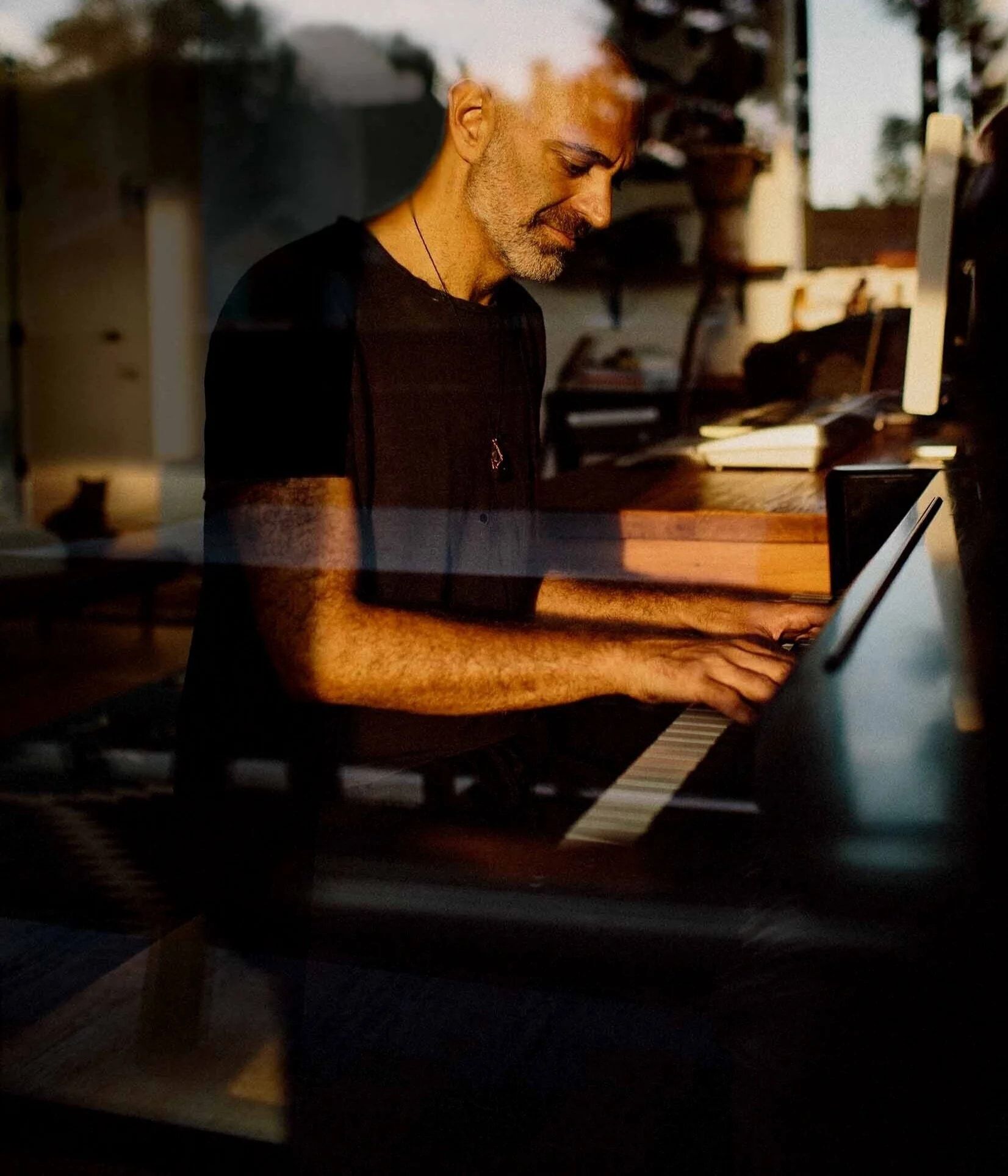 Reza Safinia playing piano in warm late-afternoon light